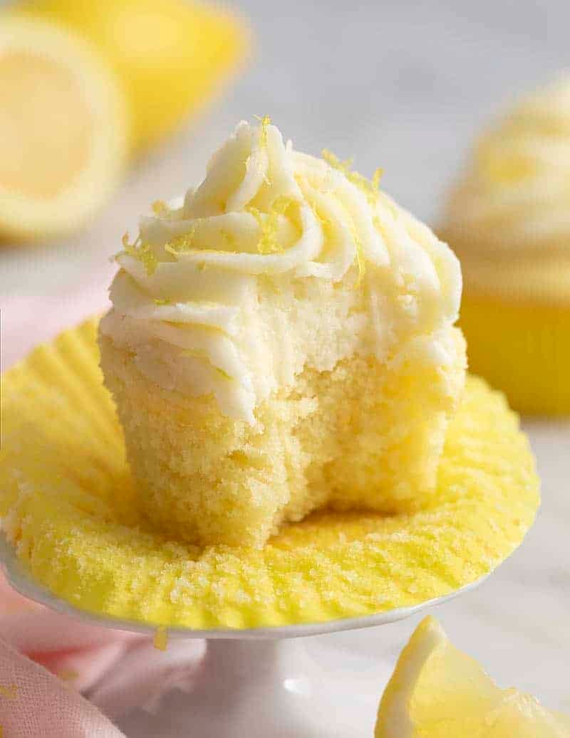 A moist, fluffy lemon cupcake with a bite taken out of it. 