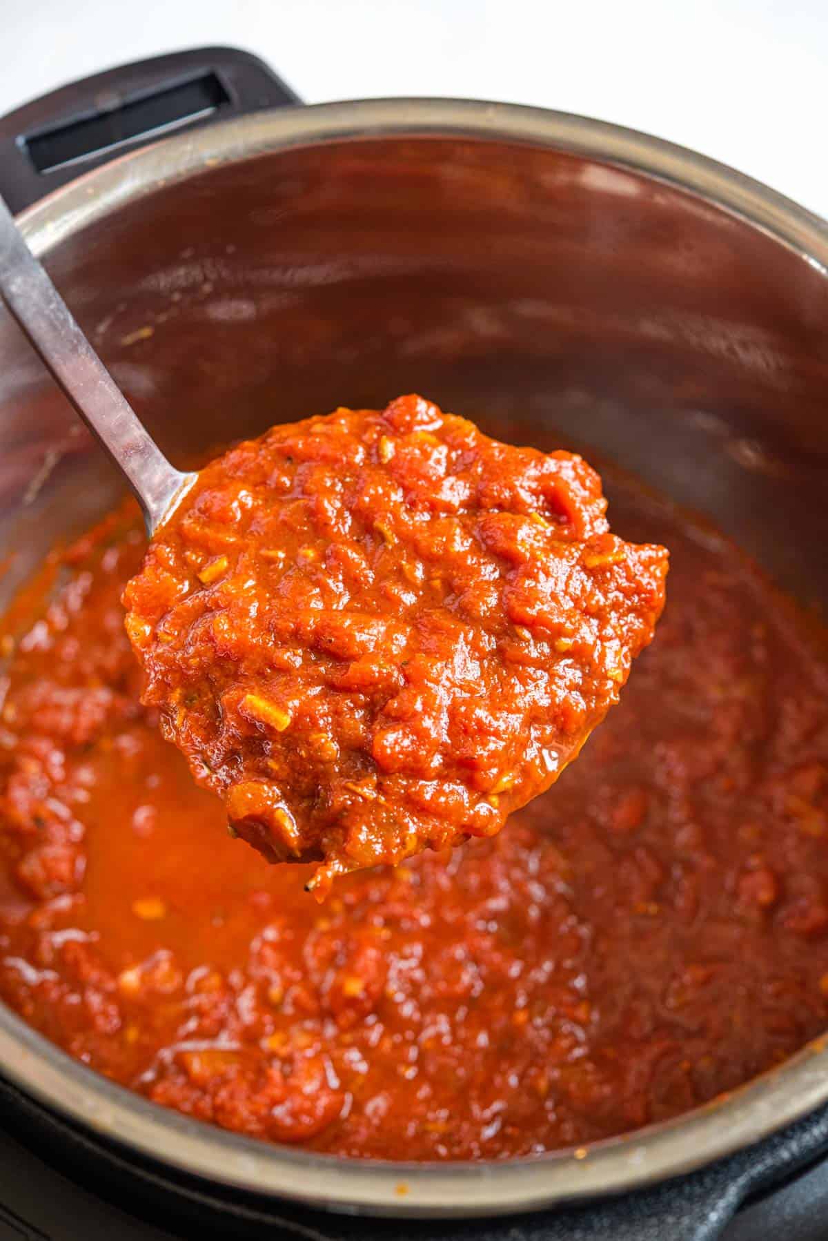 A close up of a ladle of spaghetti sauce