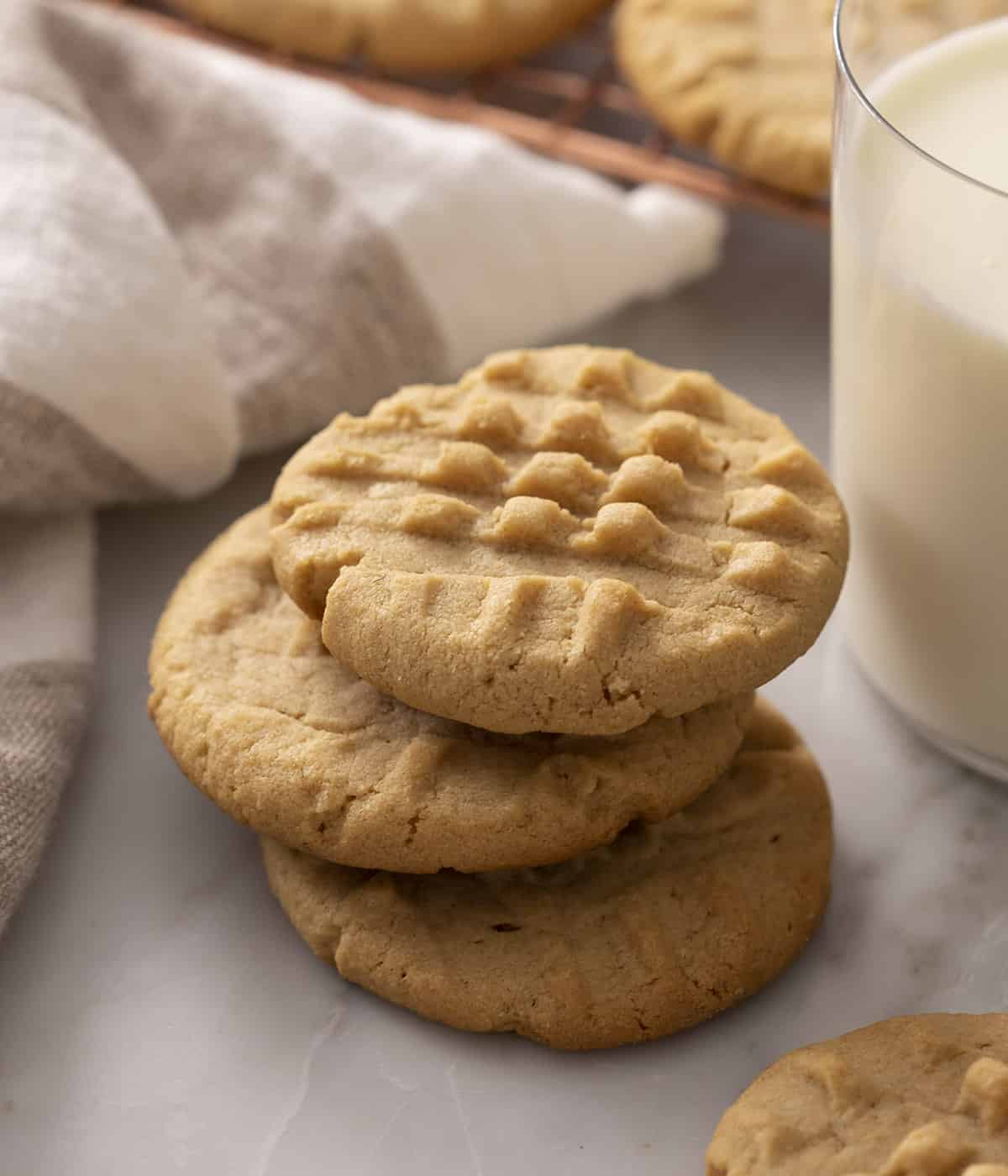 Three peanut butter cookies next to a glass of milk.