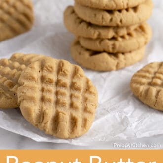 A bunch of peanut butter cookies on a piece of parchment paper.