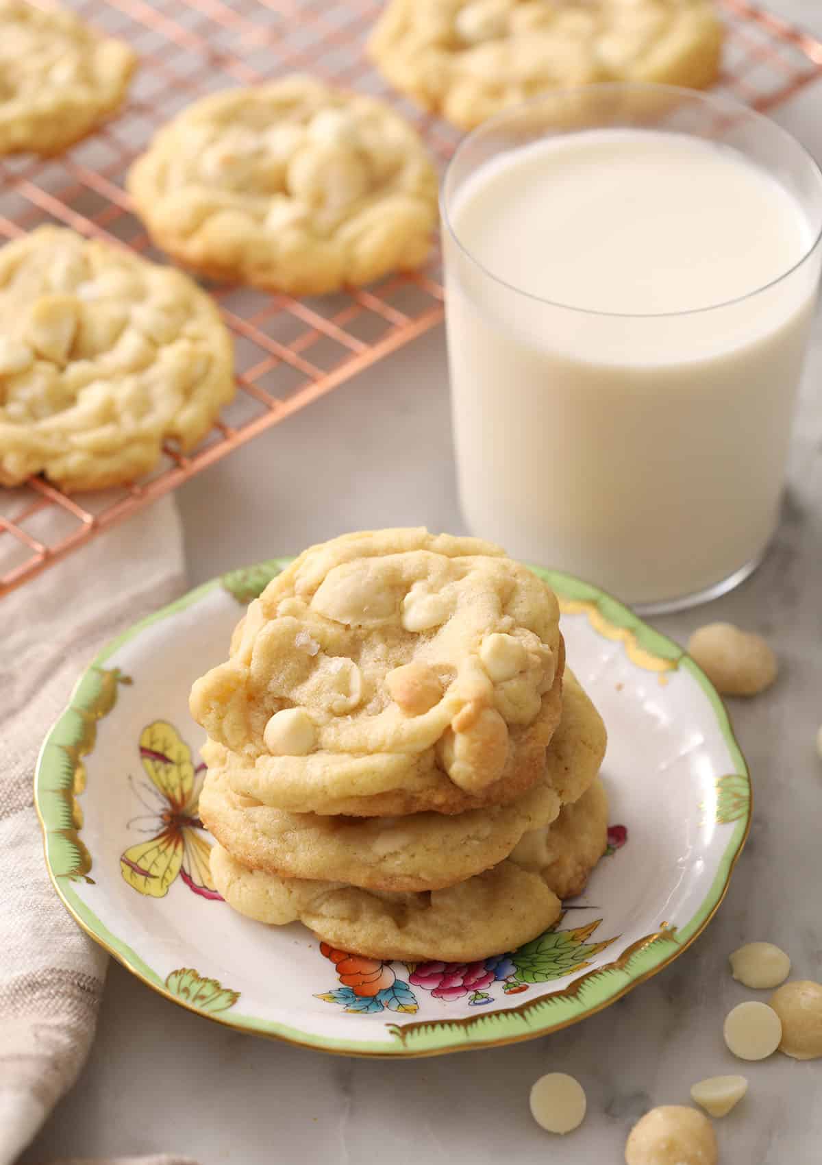 three white chocolate macadamia nut cookies stacked on a plate