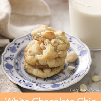 Three White chocolate chip macadamia nut cookies on a porcelain plate next to a glass of milk.