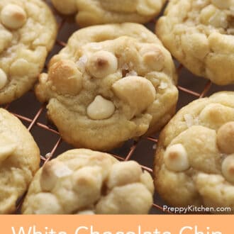 A group of white chocolate chip macadamia nut cookies on a copper cooling rack.