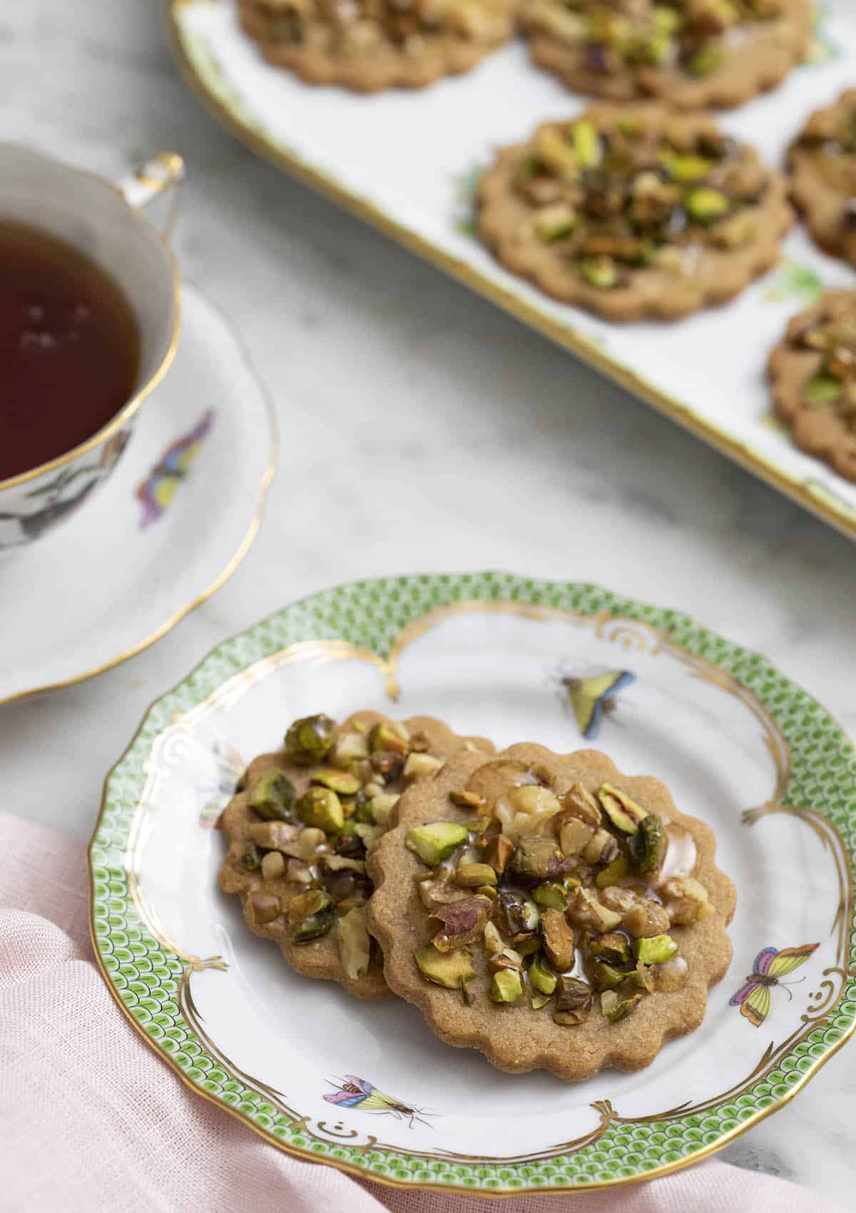 baklava cookies on a porcelain plate next to a tea cup.