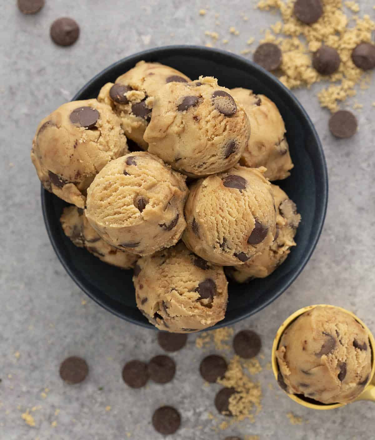 Overhead view of multiple scoops of cookie dough in a navy bowl.