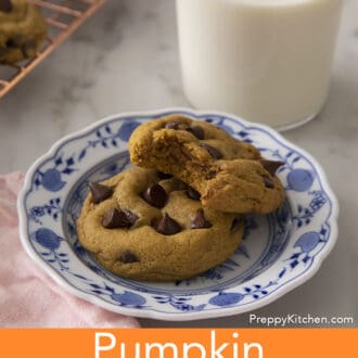 Two delicious pumpkin chocolate chip cookies on a plate next to milk.