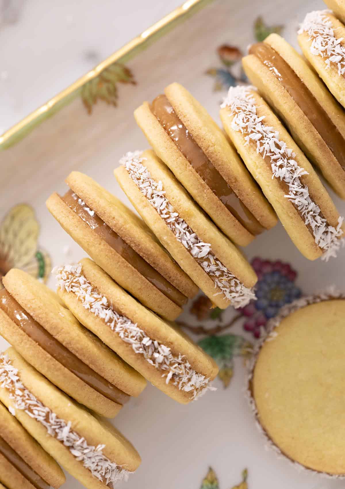 Alfajores on a porcelain serving tray, with every other one rolled in coconut.