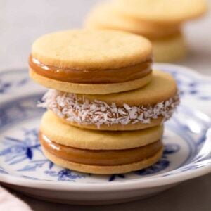 A stake of three alfajores on a blue and white plate.