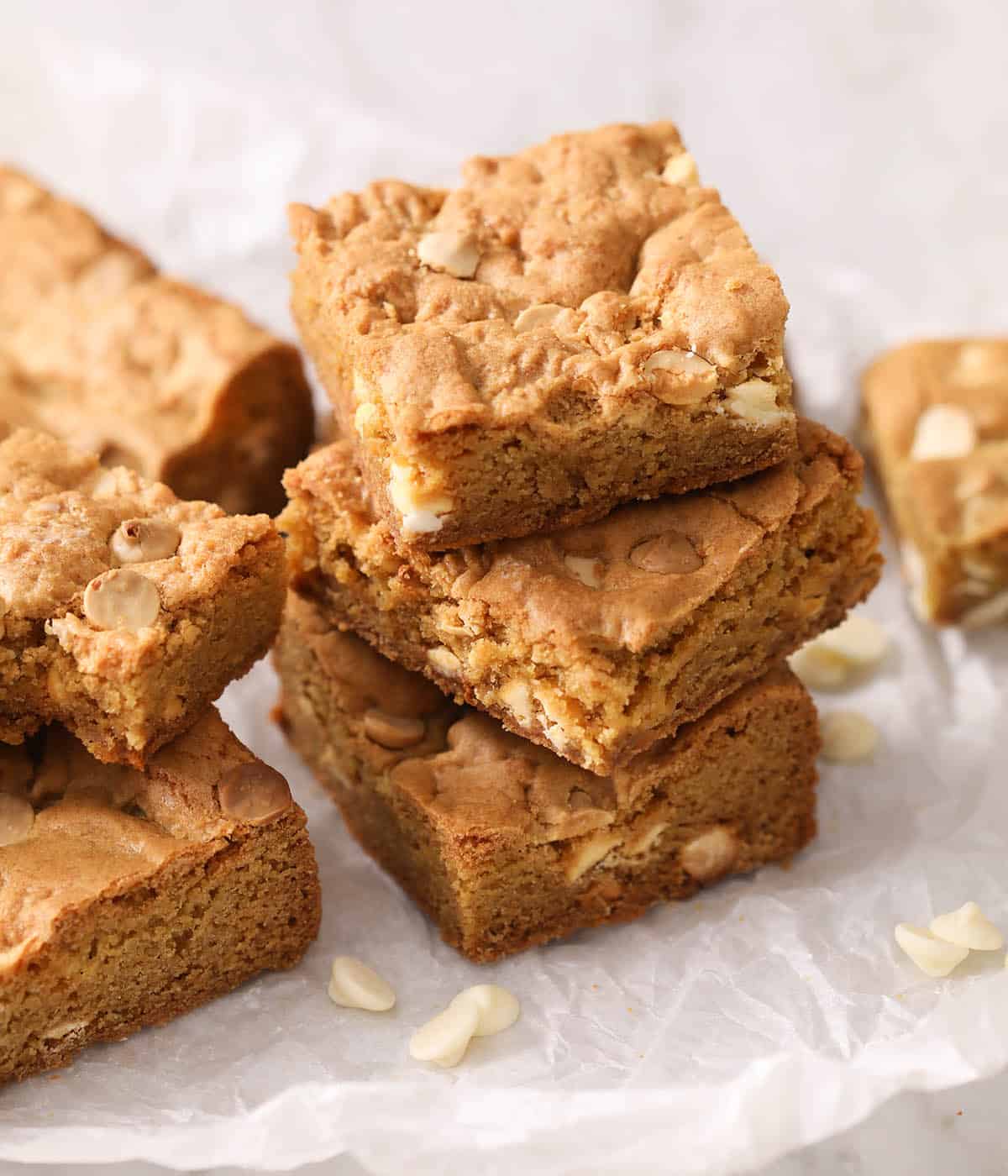 A group of blondies stacked on white parchment paper.