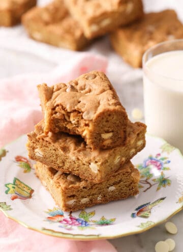 A group of blondies with white chocolate chips on a plate.