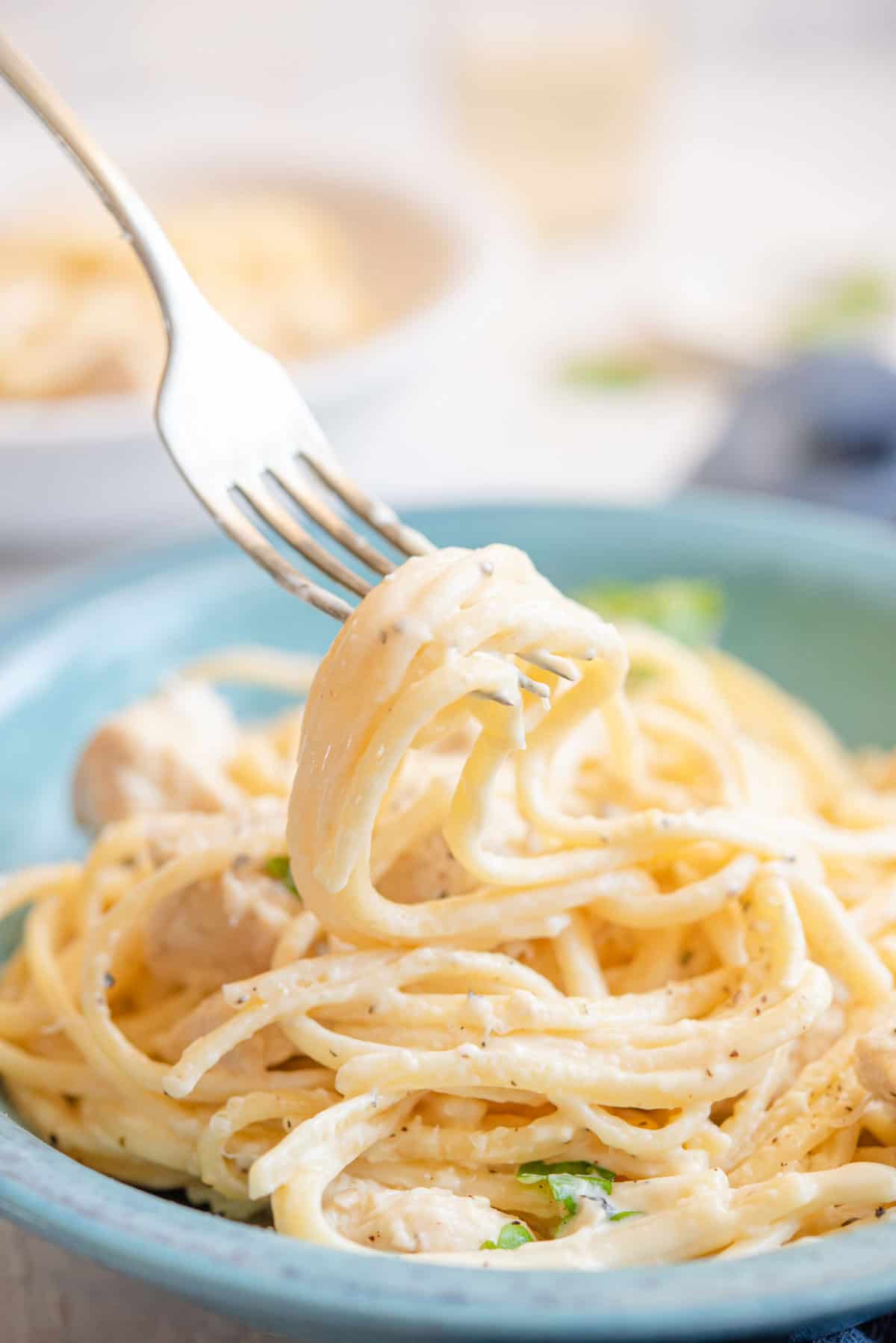 A close up of chicken alfredo on a fork