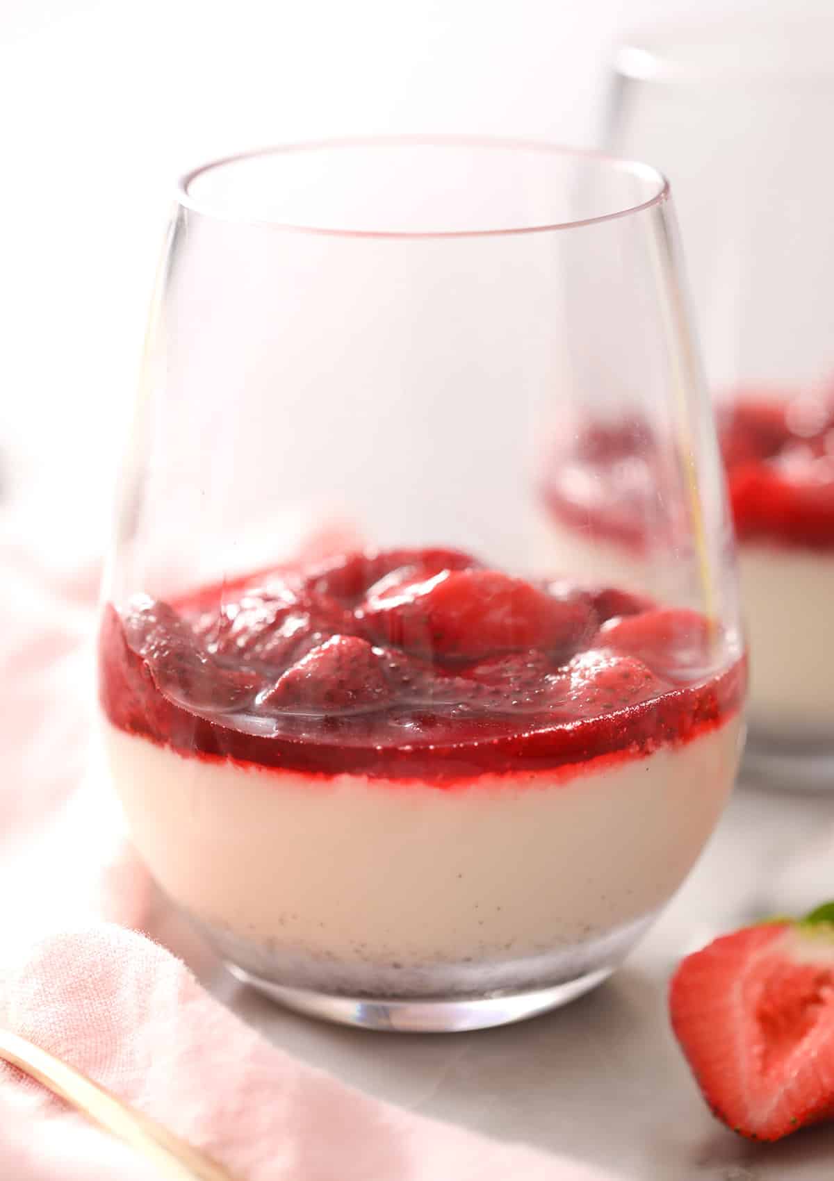a stemless wine glass with panna cotta and strawberries.