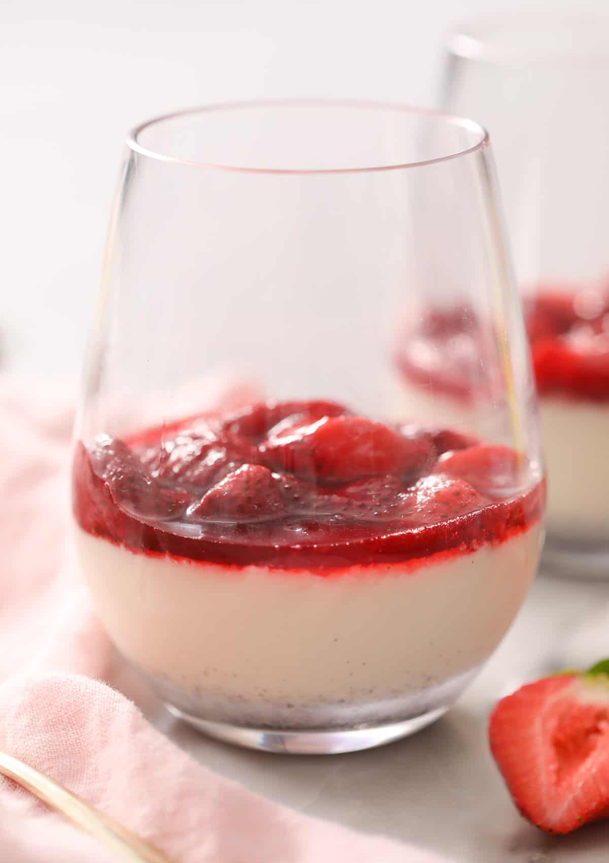 A glass of panna cotta topped with roasted strawberries.
