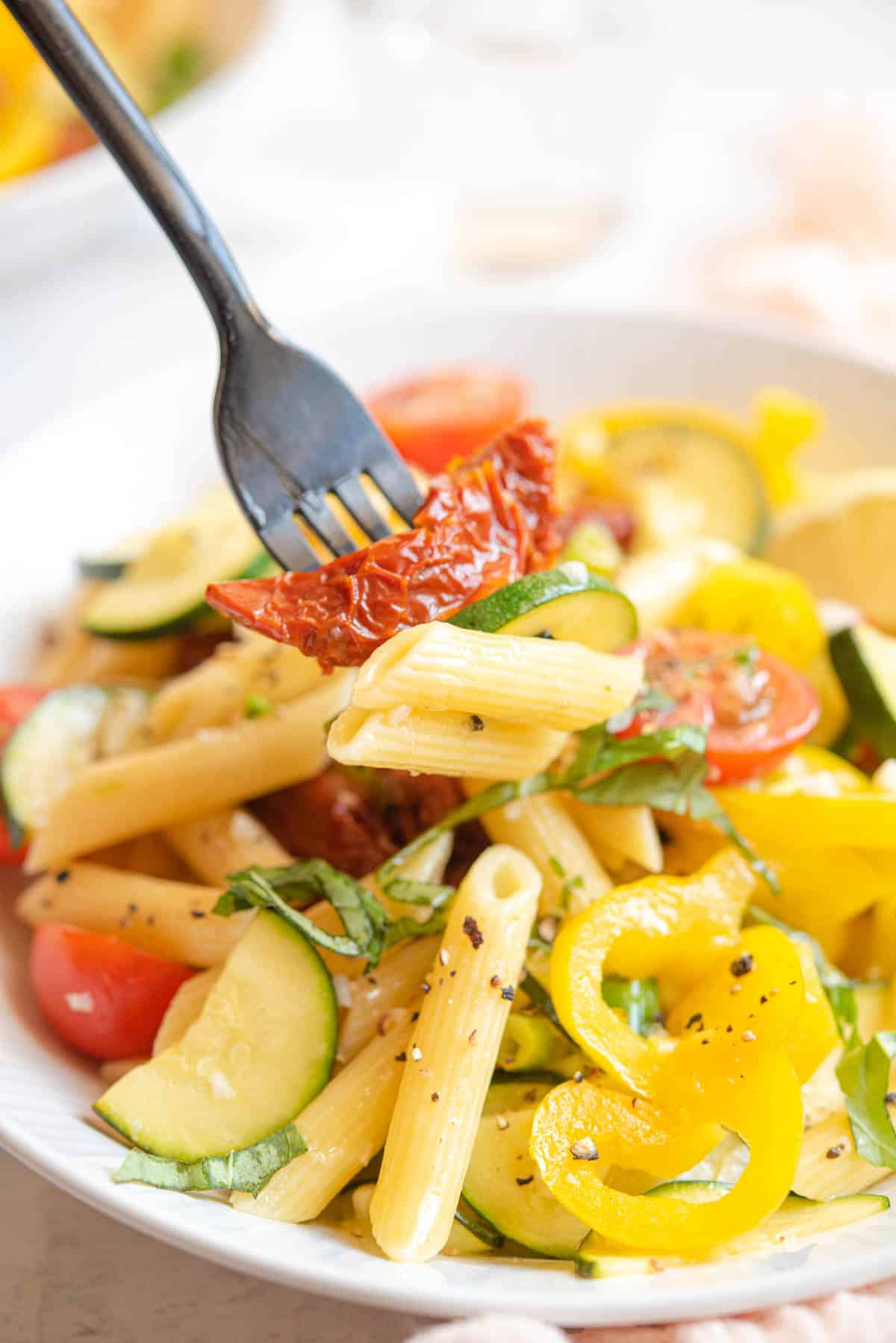 A close up of pasta and vegetables on a fork