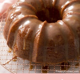 A rum cake dripping with rum sauce on a copper cooling rack.