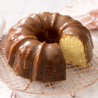 A Rum Cake dripping with rum sauce on a cooling rack.