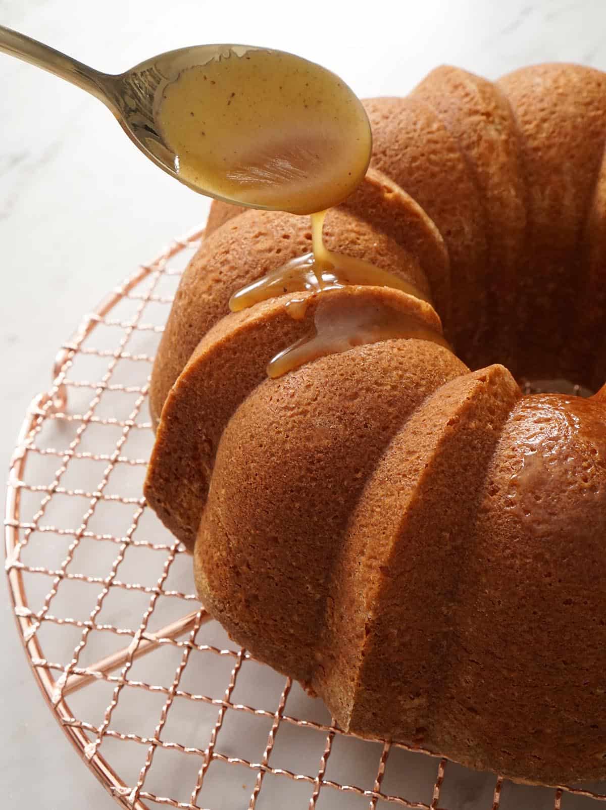 Rum sauce getting spooned onto a bundt cake.