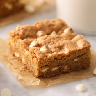 A blondie with white chocolate chips on a ppiece of parchment paper.