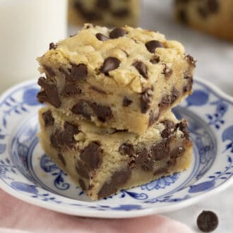 Two pieces of delicious chocolate chip cookie bars on a blue and white plate.