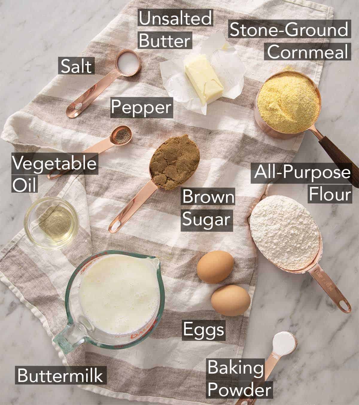 Ingredients to make cornbread on a marble counter.