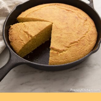 Pinterest graphic of cornbread in a cast iron skillet with a slice removed and another cut.