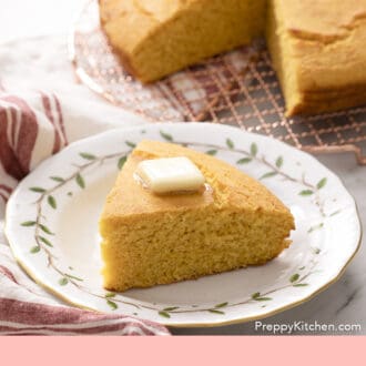 Pinterest graphic of a loaf of cornbread on a copper cooling rack with a piece in the foreground.
