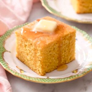 A square piece of cornbread topped with butter and honey.
