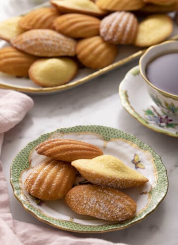 A green and white plate with Madeleines on a marble counter.
