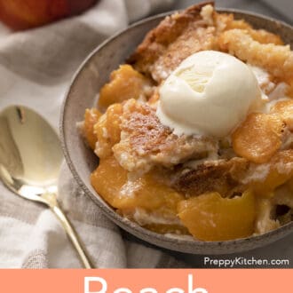 A bowl of peach cobbler next to a gold spoon.