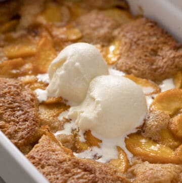 A delicious peach cobbler topped with two scoops of vanilla ice cream.