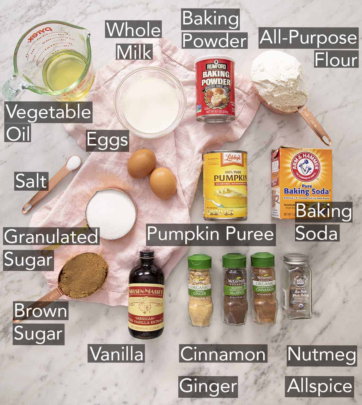 Ingredients to make pumpkin muffins on a marble counter.