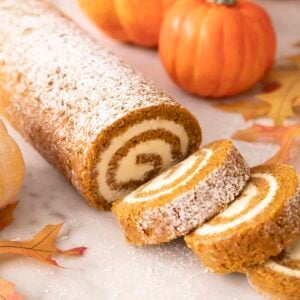 A pumpkin roll cake with three slices cut out.