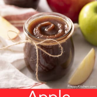 Apple butter in a glass jar on a marble counter.