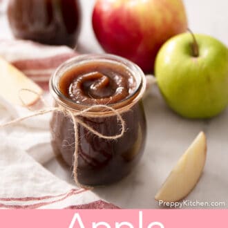 A glass jar of apple butter sitting on a counter top