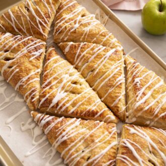 Apple turnovers arranged in a pattern on a baking sheet.