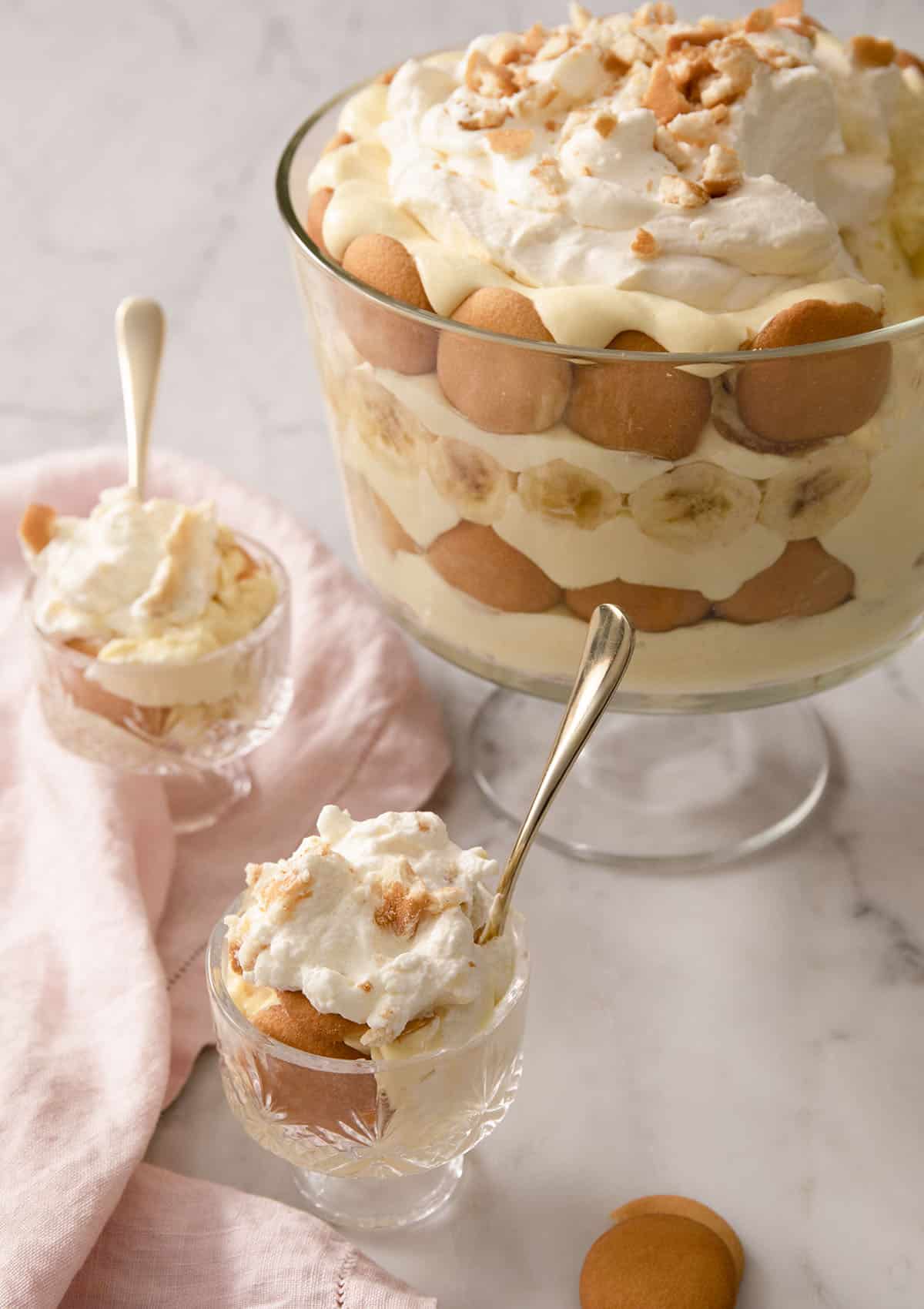 A banana pudding in a trifle dish with portions in smaller serving glasses.
