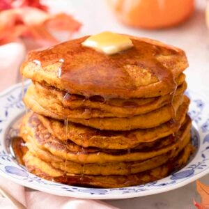 A stack of pumpkin pancakes with butter and syrup.