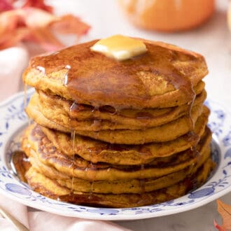 A stack of pumpkin pancakes with butter and syrup.