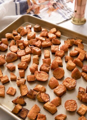 Roasted sweet potatoes on a golden baking sheet.