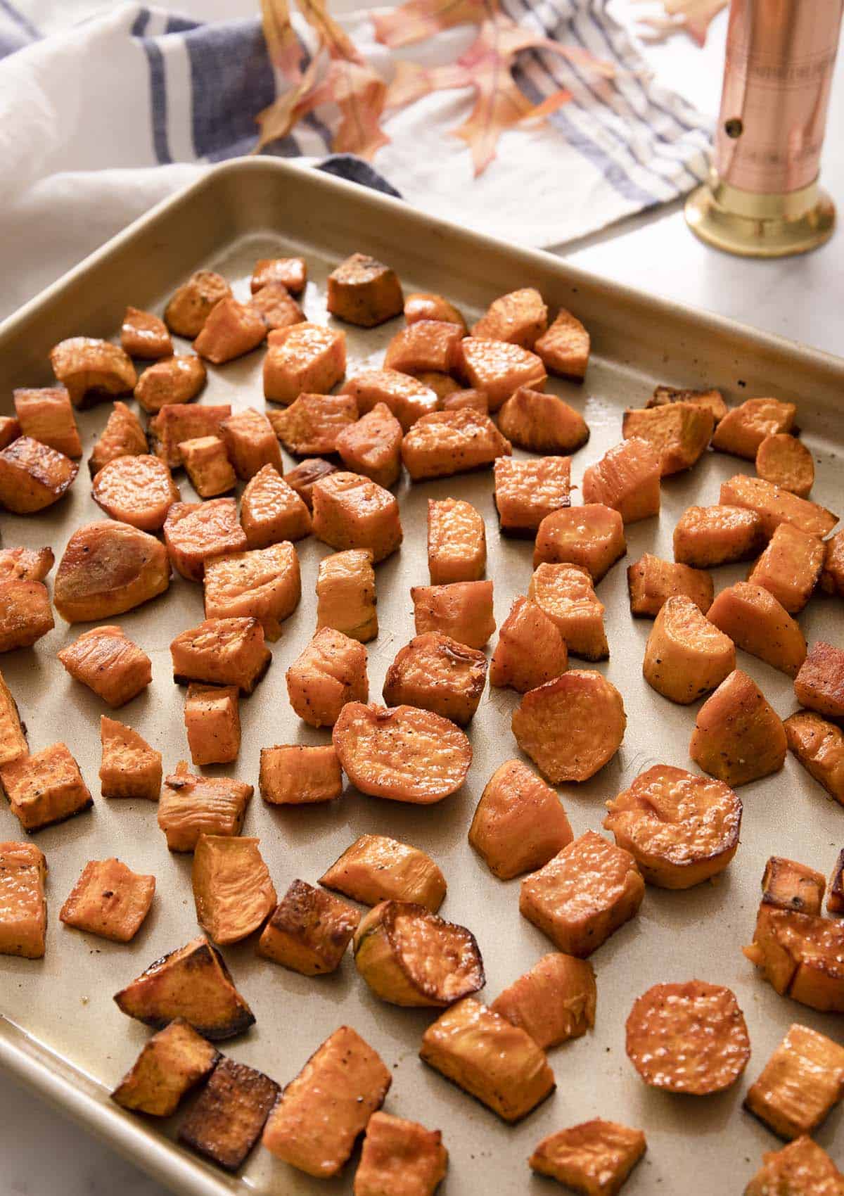 Roasted sweet potatoes on a golden baking sheet.