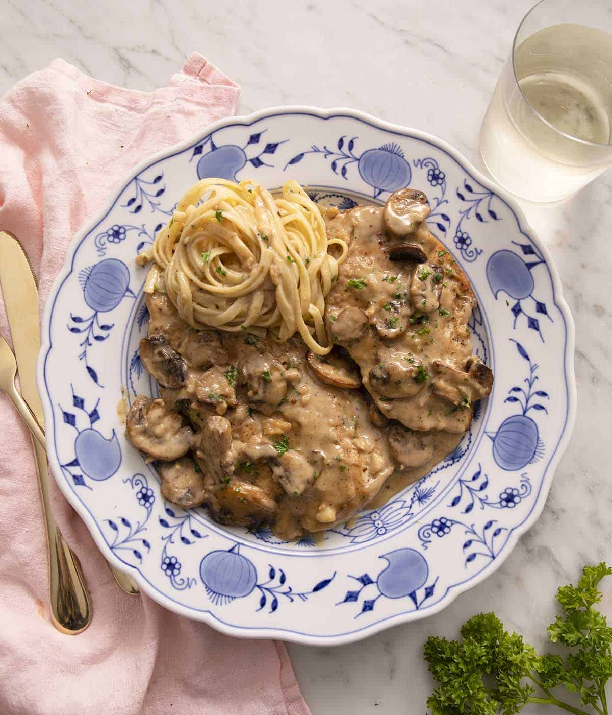 A blue and white dinner plate with chicken marsala.