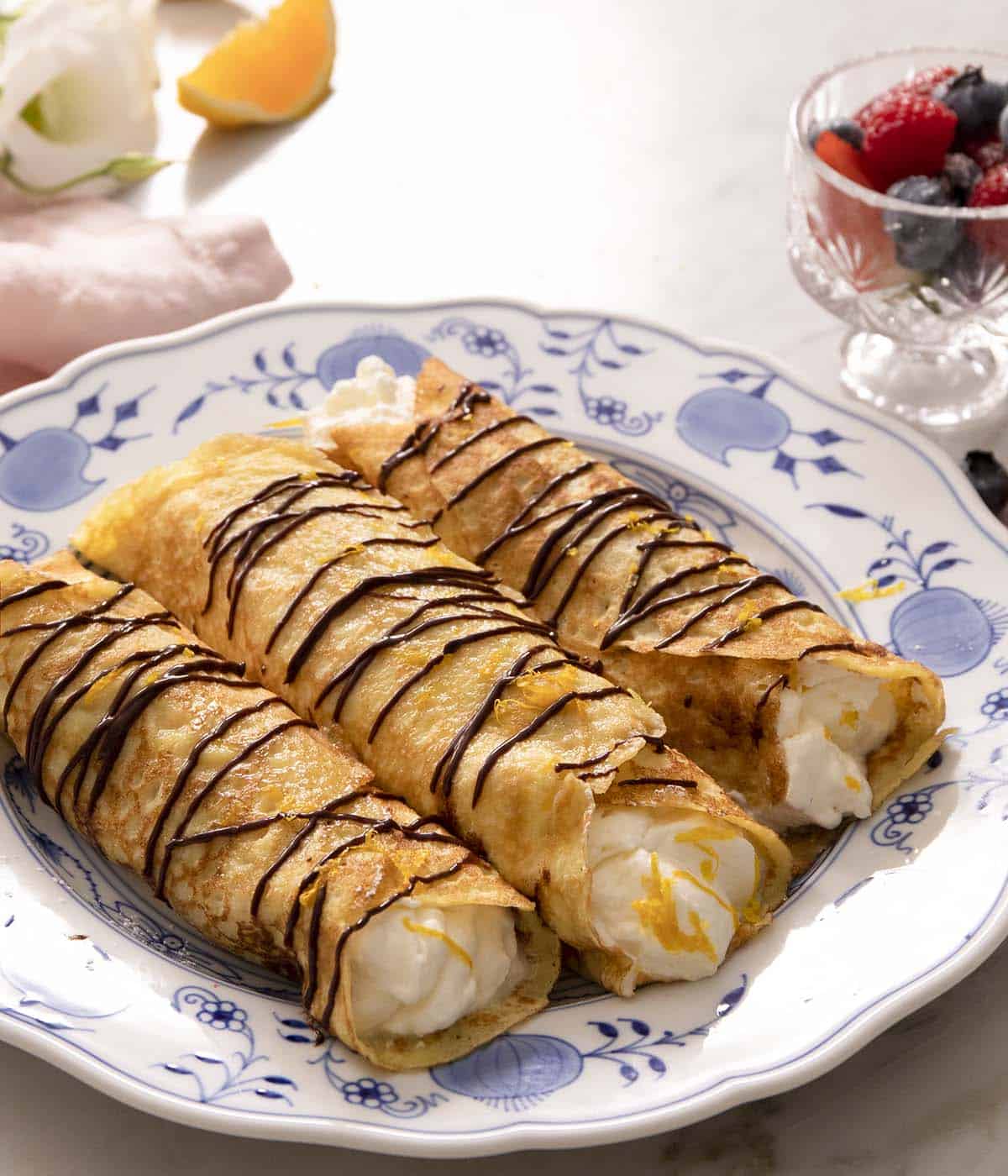 Crepes drizzled with chocolate and filled with whipped cream.