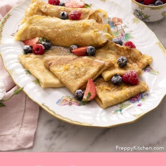 Pinterest graphic of folded crepes on a platter with berries.