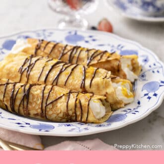 Pinterest graphic of rolled crepes on a blue and white plate with chocolate drizzle.