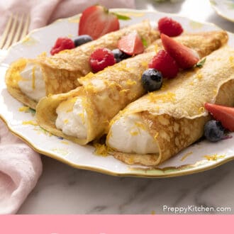 Pinterest graphic of rolled crepes filled with whipped cream on a plate with berries.