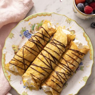 Pinterest graphic of rolled crepes on a plate with chocolate drizzle.