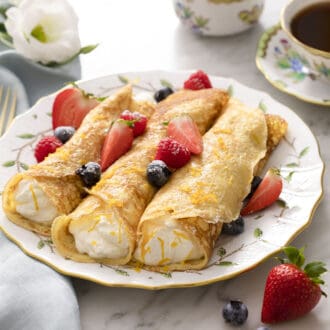 Three crepes filled with whipped cream and berries.