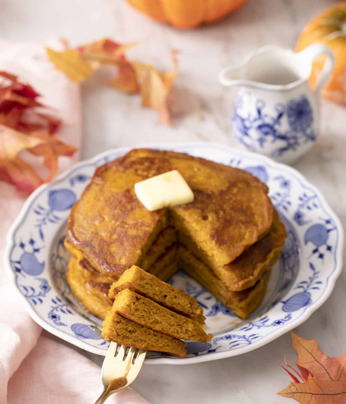 A stack of pumpkin pancakes that's been cut into with a fork.