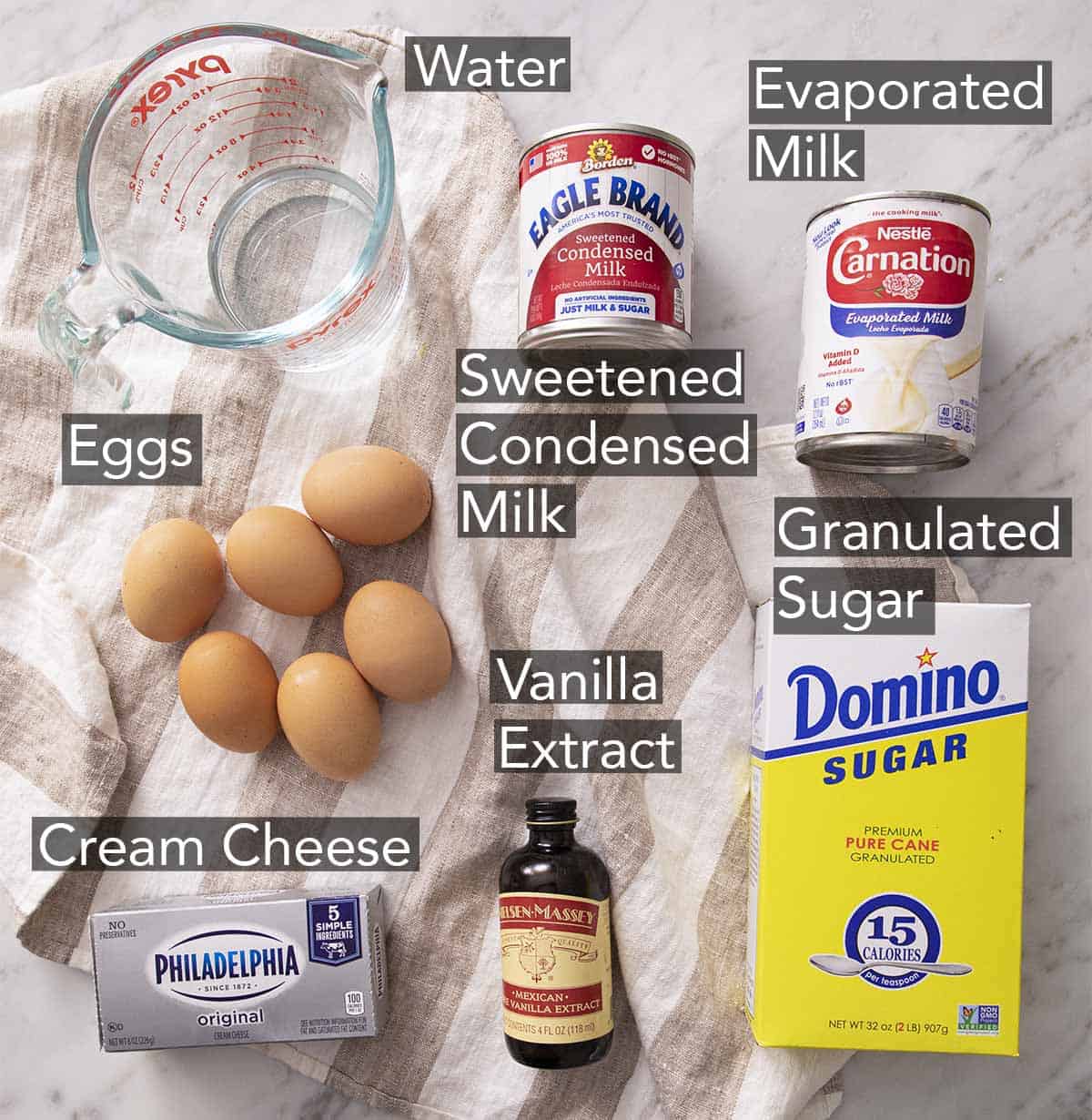 Ingredients to make flan on a marble counter.