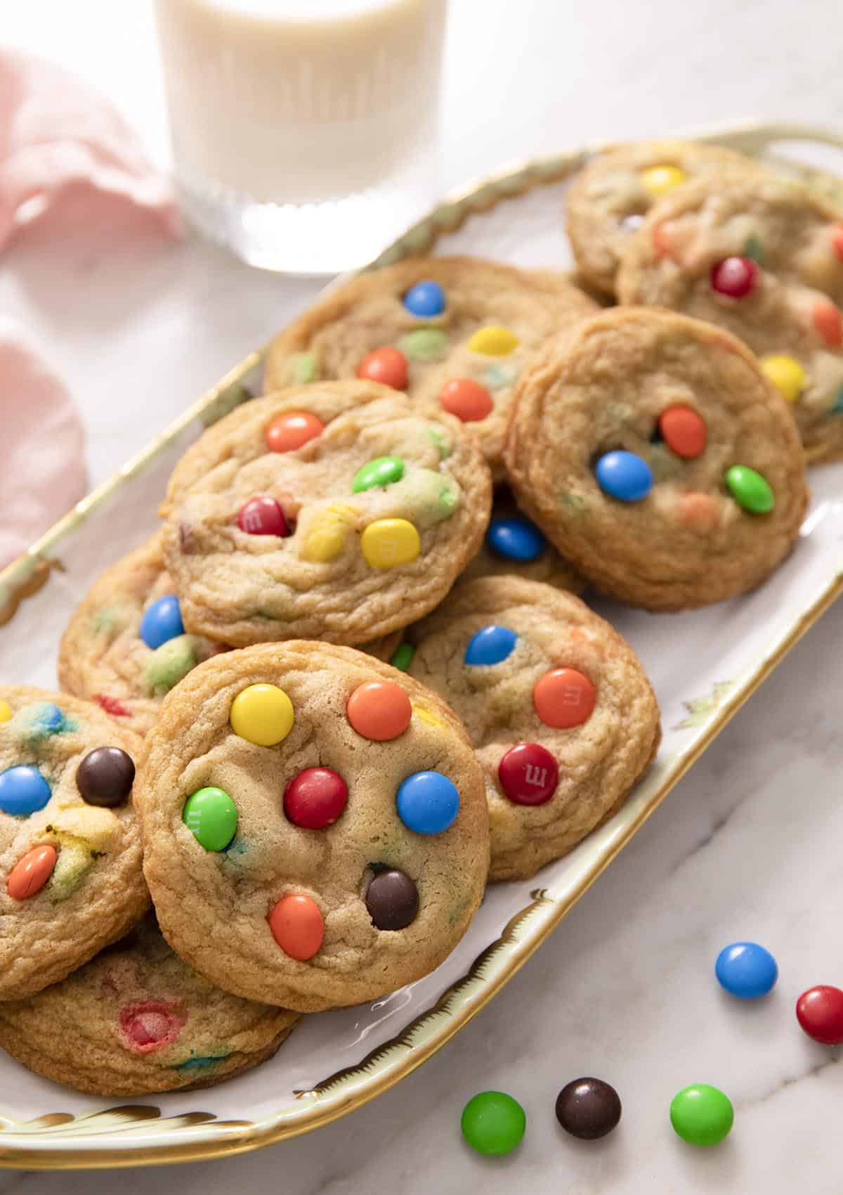 A group of M&M cookies on a porcelain serving tray.